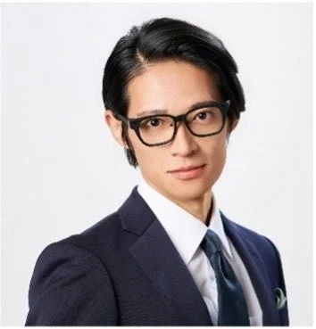 黒縁眼鏡にネイビーのスーツ姿の久保裕丈氏のポートレート