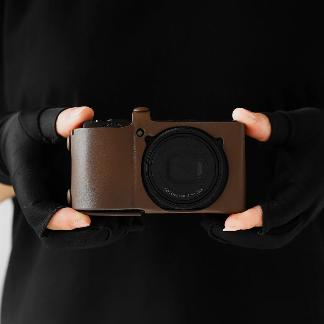 ブラウンのレザーカバーを着けたRICOH GR IVを両手で持つ様子