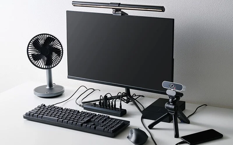 デスク上のモニターに接続された10ポートUSBハブと周辺機器