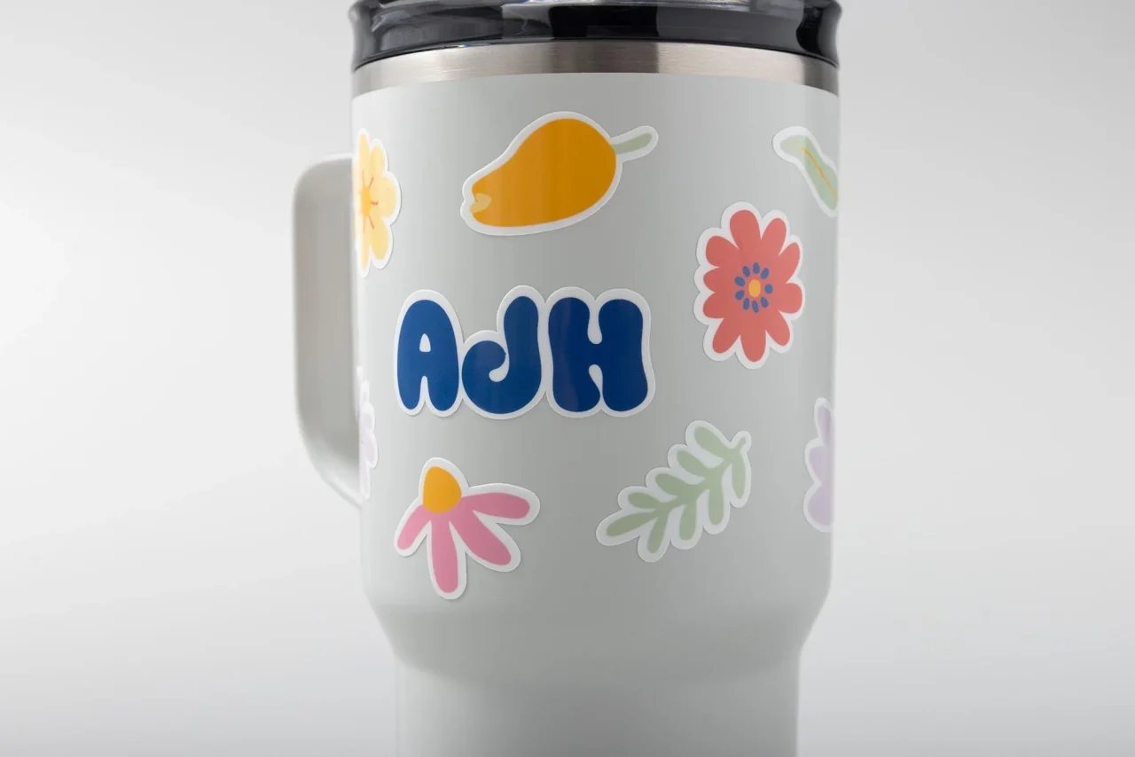 花や葉のステッカーと「AdH」文字を貼ったタンブラー