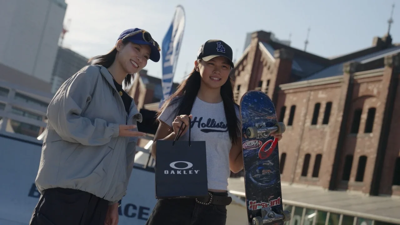 Oakley Meta Baseの会場で、OAKLEYの紙袋とスケートボードを持つ二人