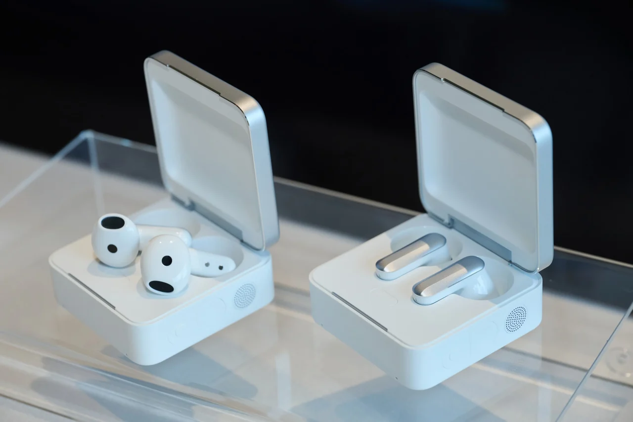 蓋を開けた白い充電ケース2つ。左は白いイヤホン、右は銀色の細長いイヤホン