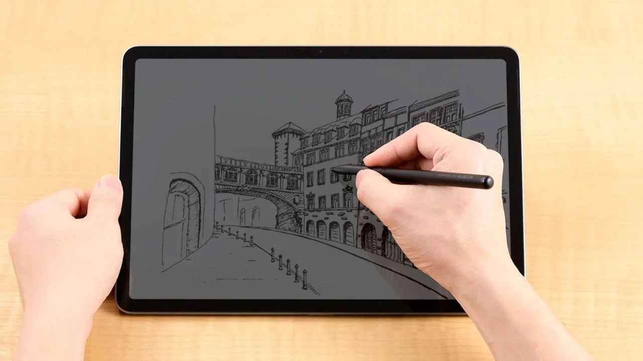 タブレットに黒いタッチペンで建物の街並みを描く手元