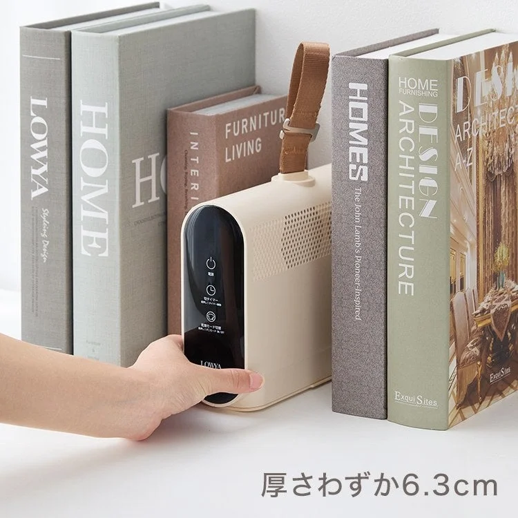 本の間に置かれたミニ衣類乾燥機。厚さわずか6.3cmのオフホワイト本体