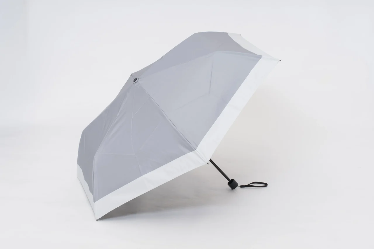 晴雫の晴雨兼用日傘。グレーの生地に白い縁取りの開いた折りたたみ傘
