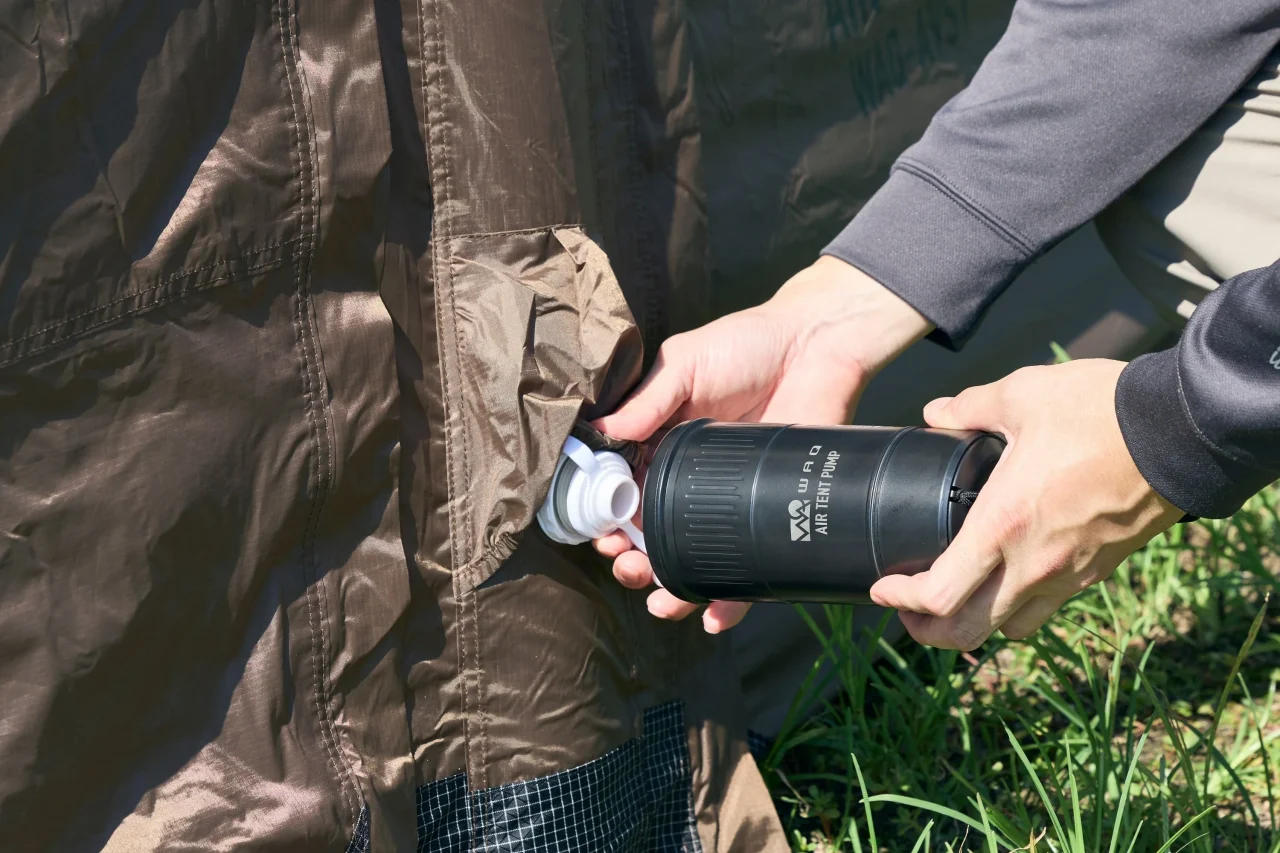 茶色いテントのバルブにAIR TENT PUMPを接続する手元