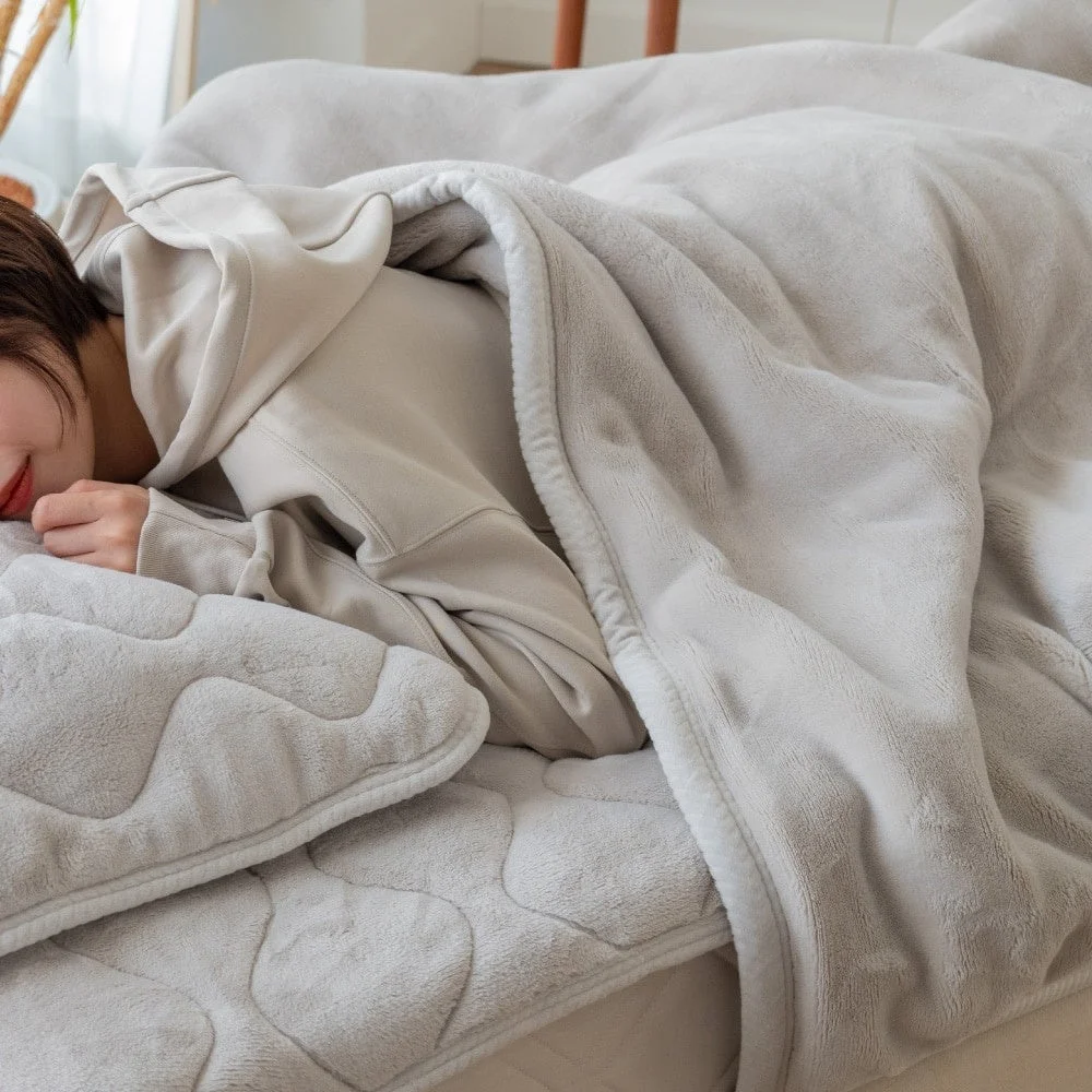 2枚合わせ中わた毛布 BUTTERをかけて横になる人とグレーの敷パッド