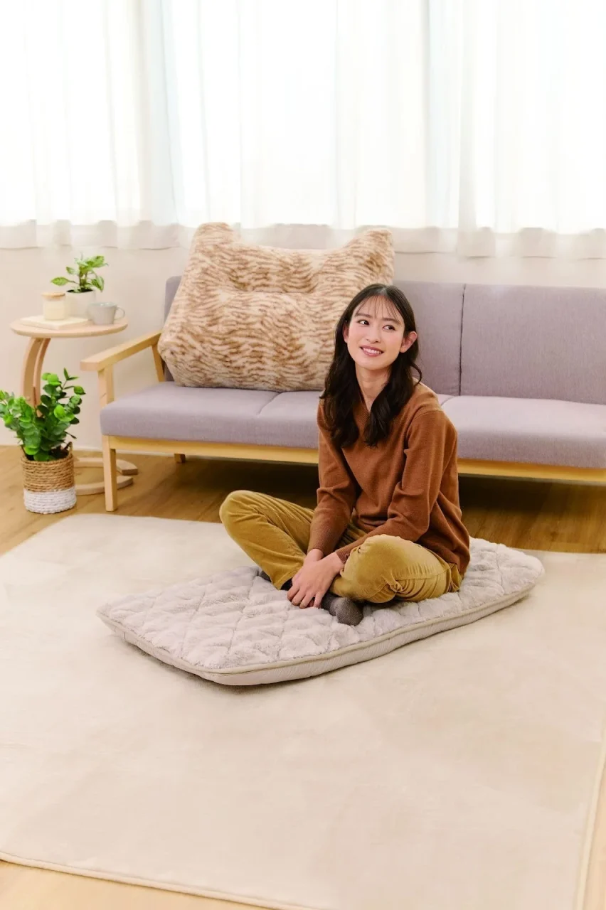 ほぼネコソファクッション。ソファ上の毛足の長い大きなクッションと女性