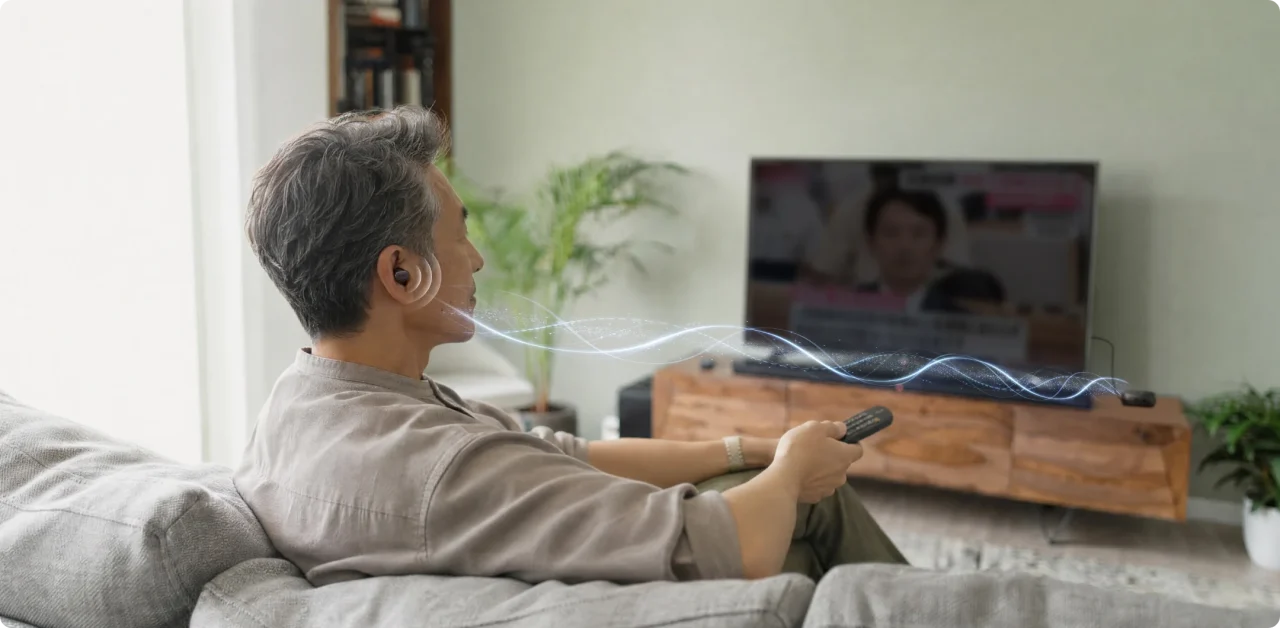 テレビ直結AUX端子の利用例。ソファでテレビの音声を耳に届ける男性