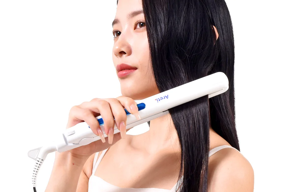 白いAreti.のヘアアイロンで黒髪をストレートに整える女性