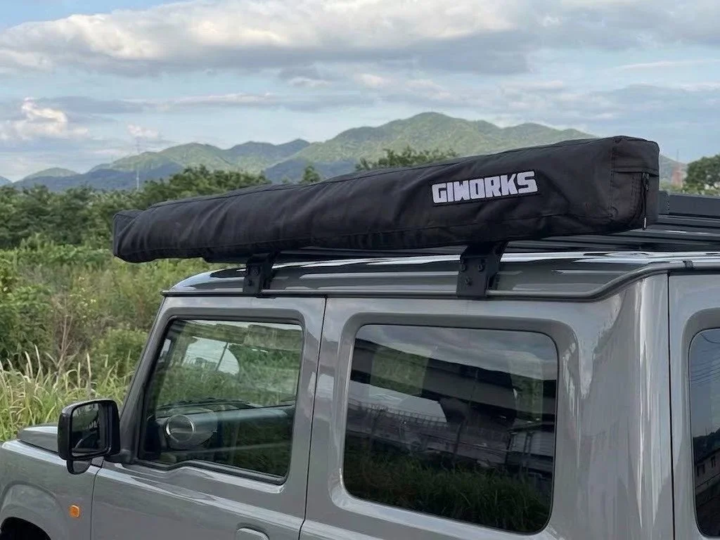車のルーフに取り付けた黒いGIWORKSのコンパクト収納状態のオーニング