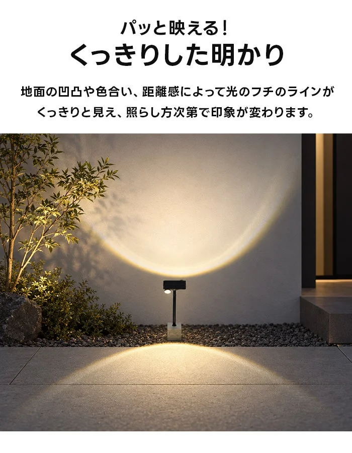 Twinのソーラーライトが壁と地面を暖色の光で照らす夜の外構