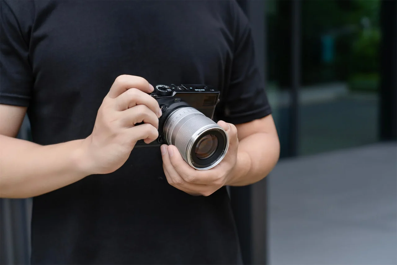シルバーのTTArtisan AF 75mm f/2を装着したカメラを両手で構える人物