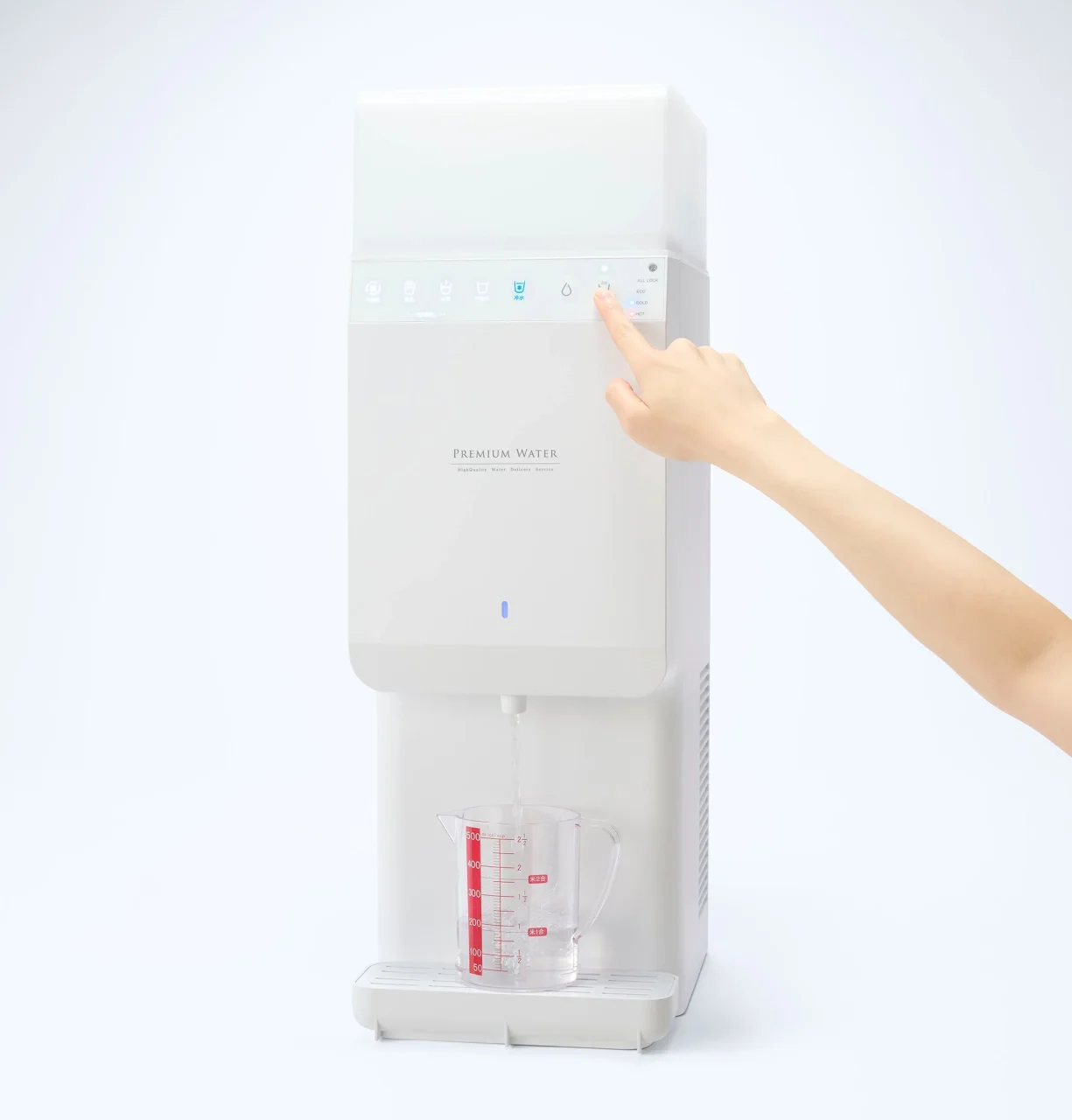 定量出水機能を搭載したウォーターサーバーのボタンを押し、計量カップに注水する様子