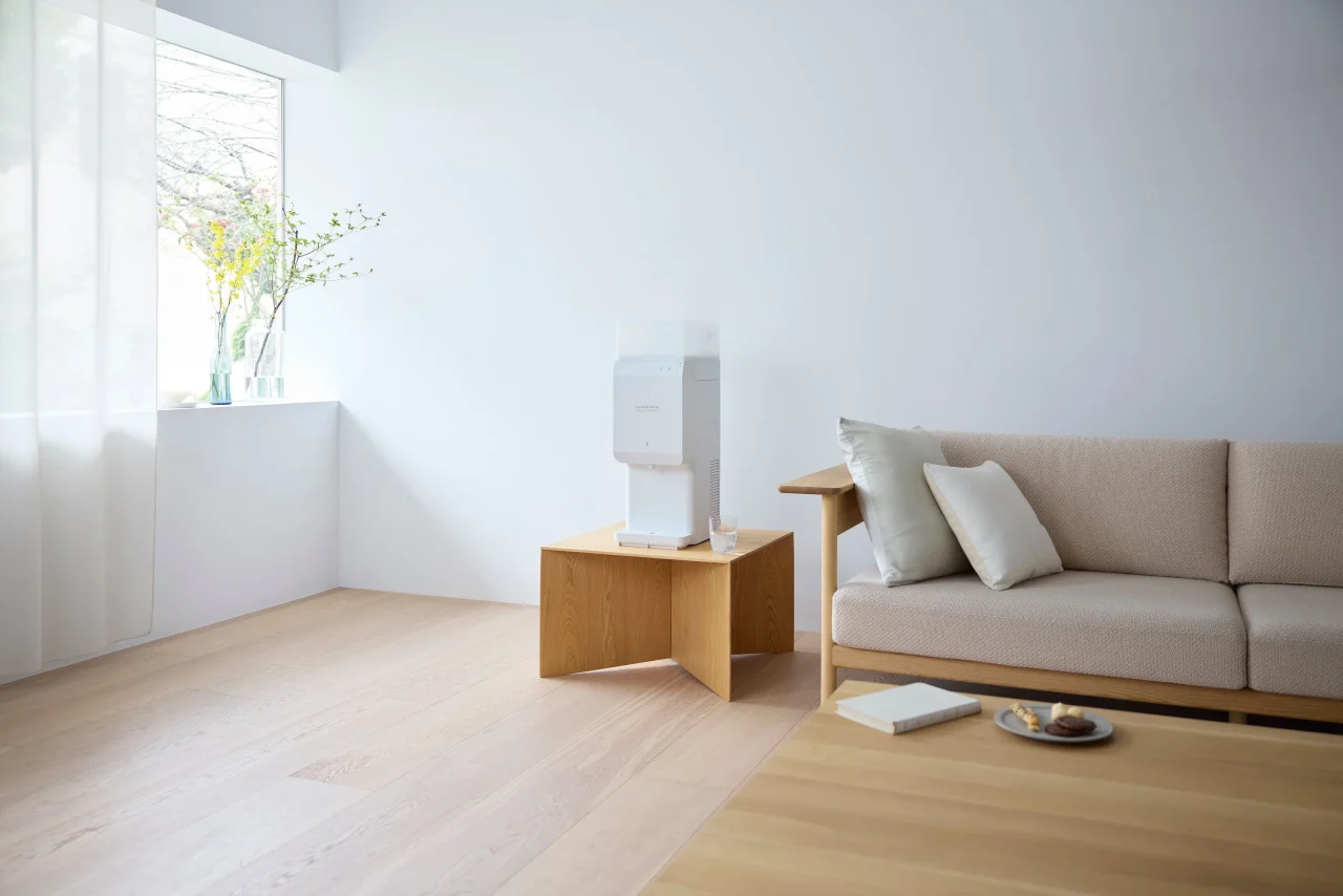 白い壁の明るい部屋で木製のサイドテーブルに置かれた白いウォーターサーバー