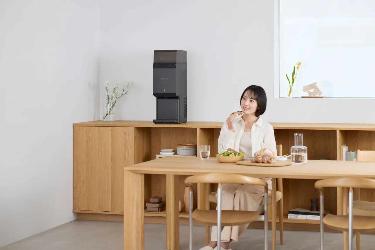 木製の棚の上に置かれたウォーターサーバーと、食卓で食事する女性
