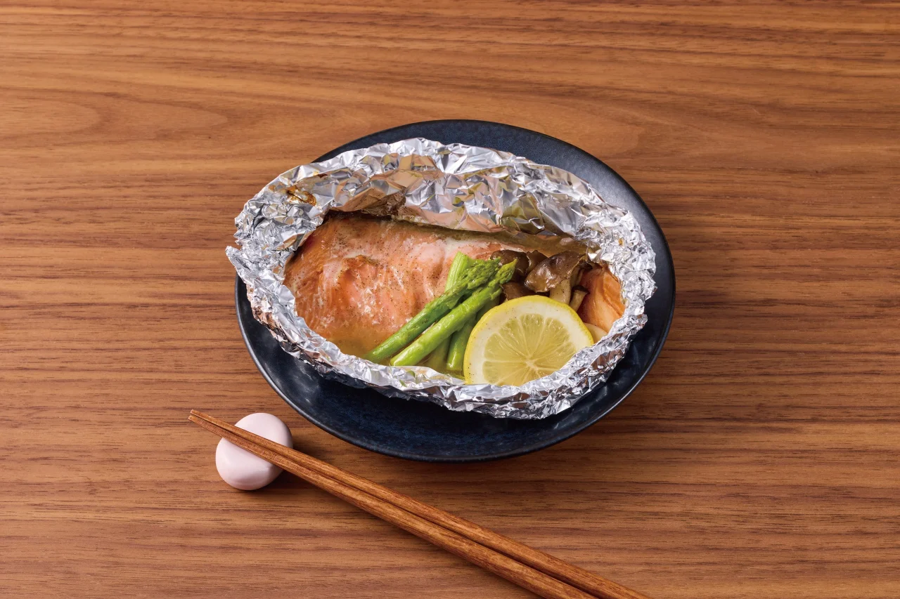 アルミホイルに包まれた鮭とアスパラ、レモンの料理