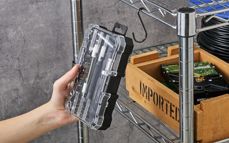 フック穴付きの専用ケースを手で持ち、金属ラックに掛ける様子