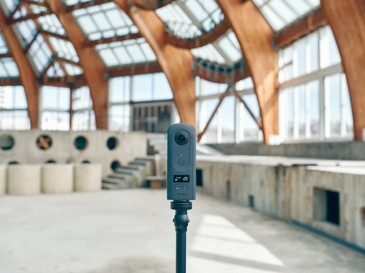木造アーチ構造の建物内に三脚で設置されたRICOH360 THETA A1