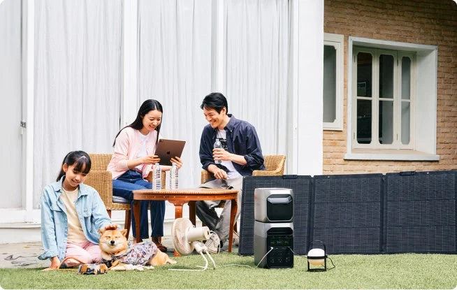 庭で家族と柴犬がポータブル電源とソーラーパネルのそばで過ごす様子