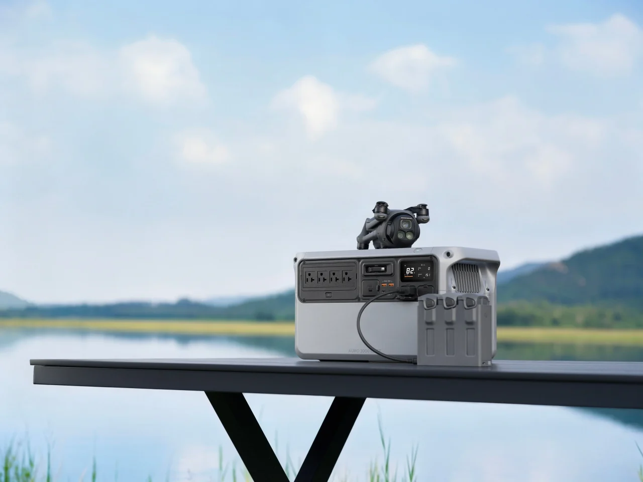 湖畔のテーブル上のポータブル電源とドローン、バッテリー充電ハブ
