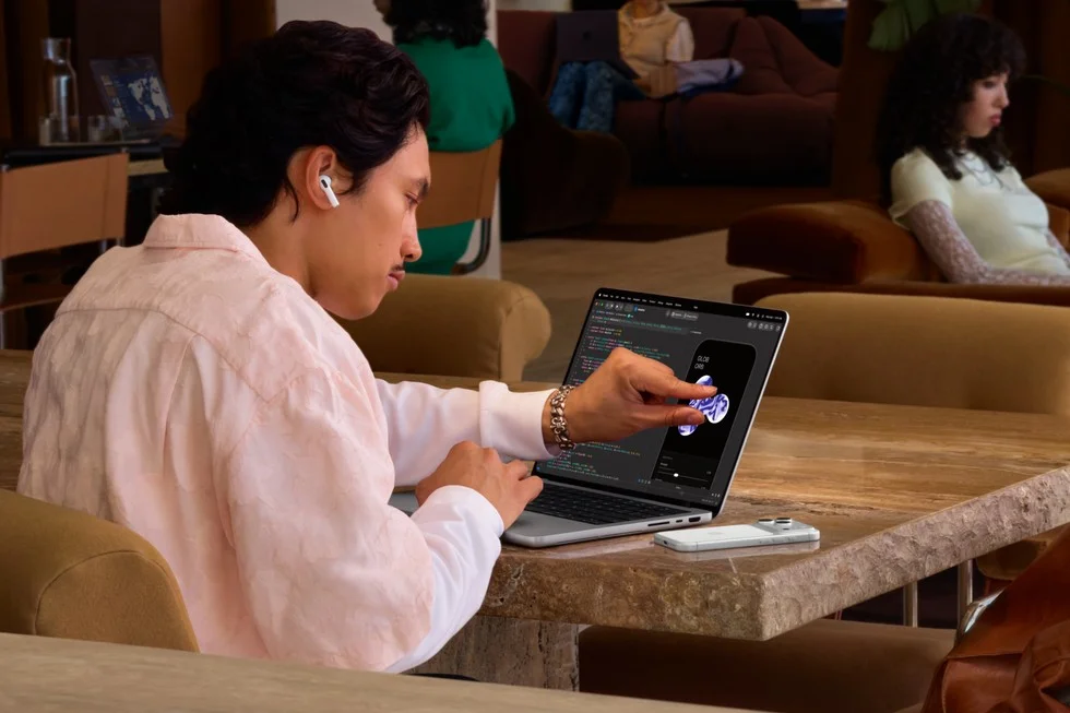 カフェでMacBook Proの画面に指で触れて操作する男性