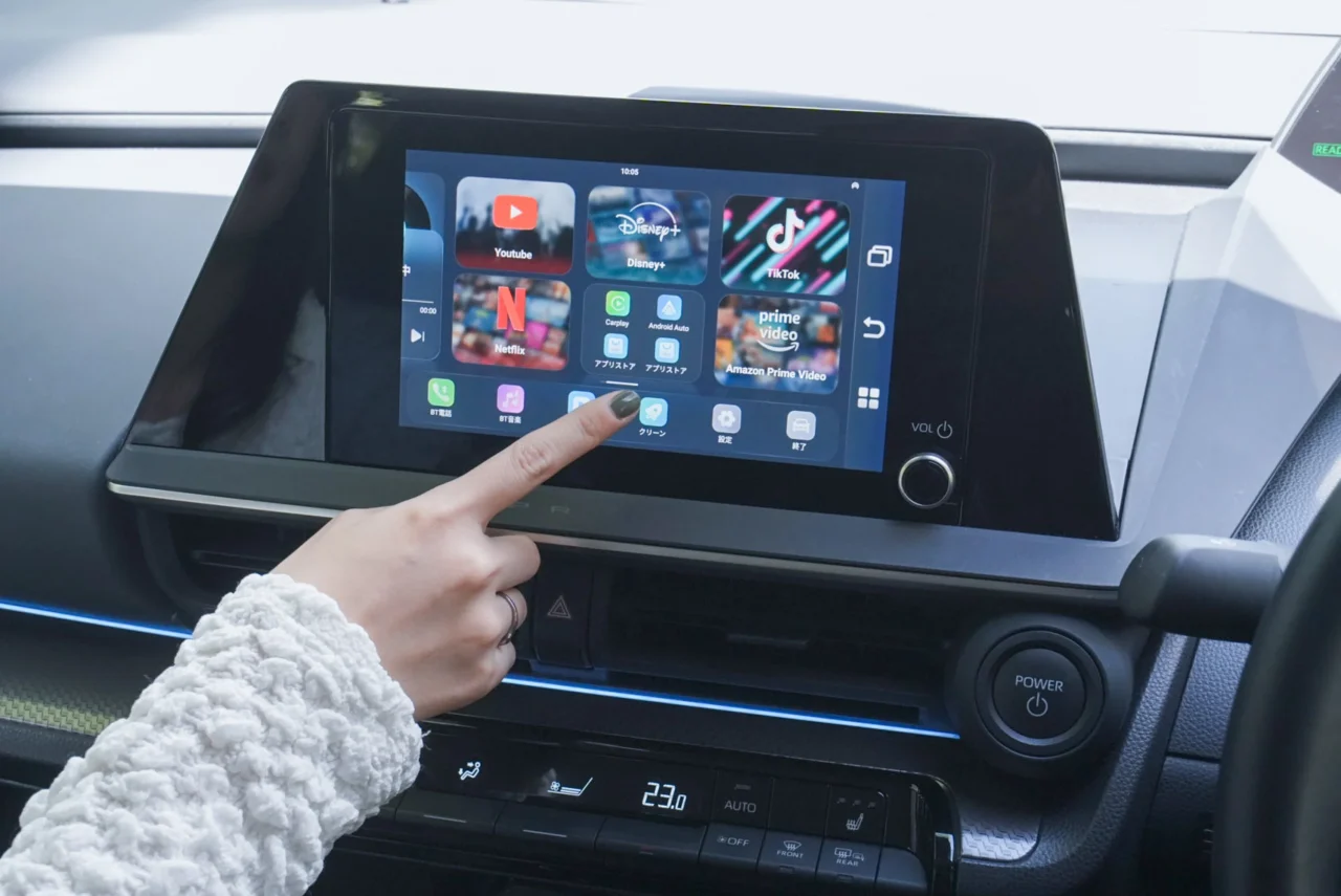 Ottocast Play2Video S対応の車載ディスプレイのアプリ画面を指で操作する様子