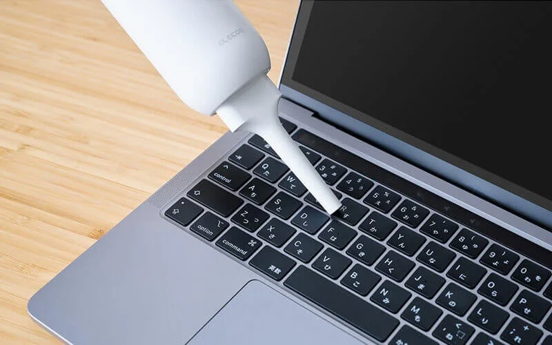 細ノズルでノートPCのキーボードのすき間を掃除する白いクリーナー
