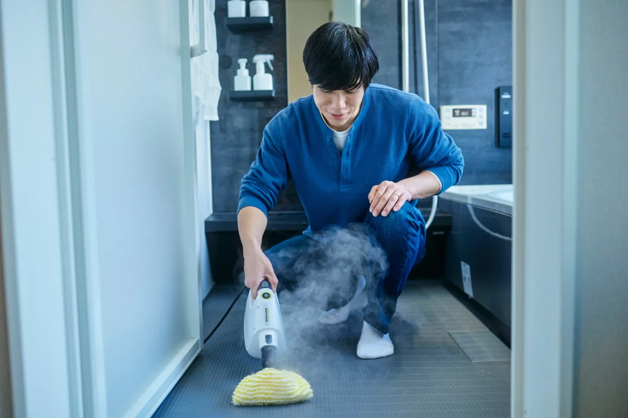 浴室でスチームクリーナーを床に当てて掃除する男性の利用シーン