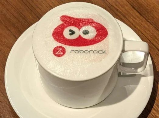 Roborock カフェ・ラテ。ロゴと赤いキャラクターがプリントされた白いカップ